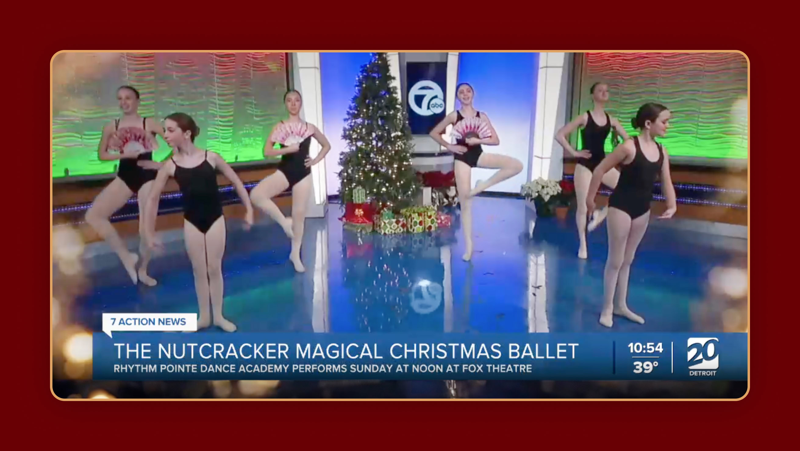 Dance performance on a television news program for Channel 20 Detroit, featuring ballet dancers in black outfits posing beside a Christmas tree, with news graphics displayed.