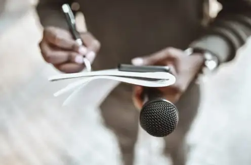 A person taking notes while holding a microphone.