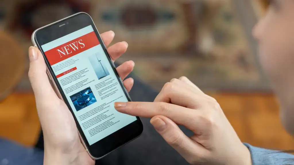 A person holding a smartphone with a news app open.