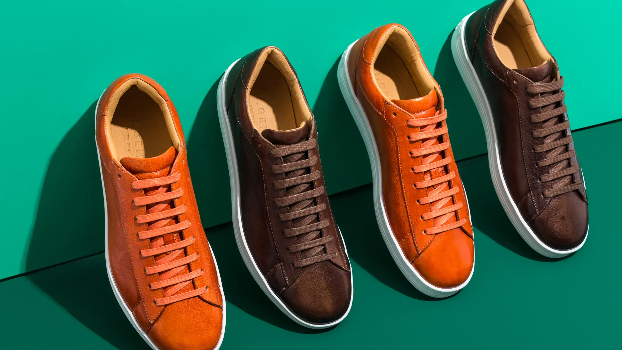 Three pairs of brown, orange and black sneakers.